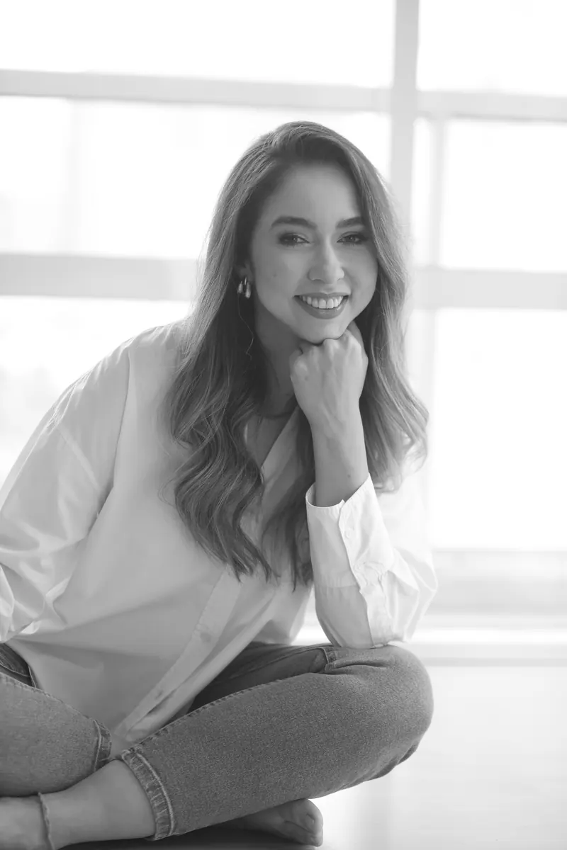 Dra. Fernanda Bardi sorrindo, com a mão no queixo, em foto preto e branco